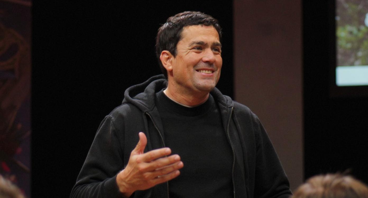 A man in a black hoodie smiling.